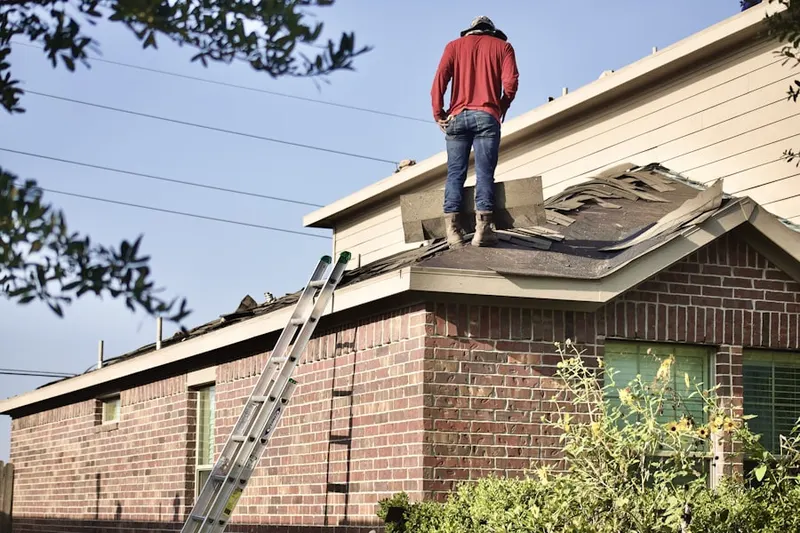 Professional roofer working on a residential roof in Bee